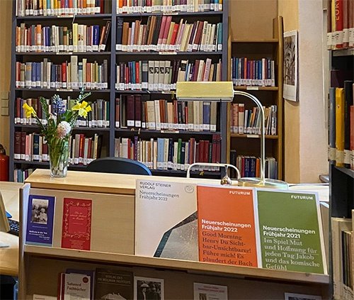 Die Ausleihtheke der Bibliothek mit Blumen und Verlagsprospekten