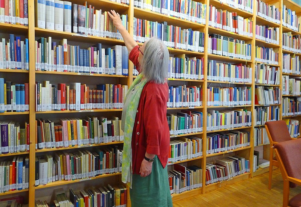Eine Besucherin greift nach einem Buch in den Regalen der Bibliothek im Rudolf Steiner Haus